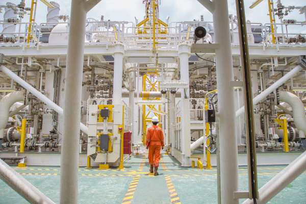Worker in orange coveralls walks through industrial facility