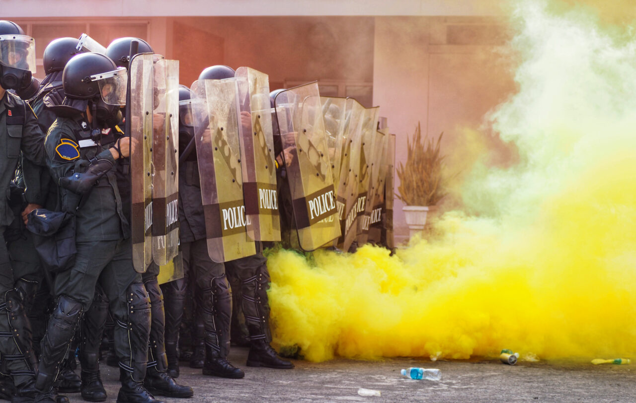 Riot police with shields amid yellow smoke