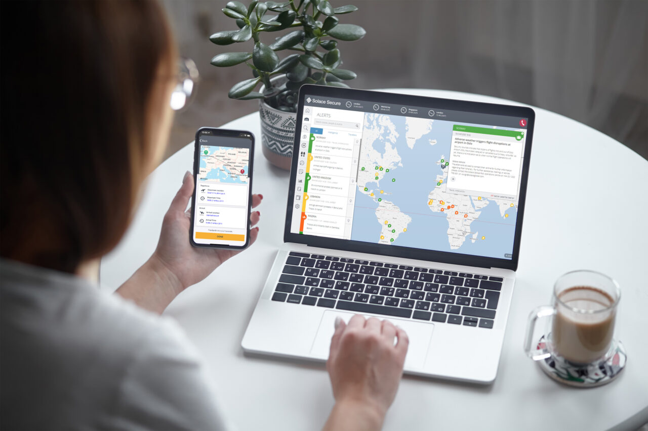 Woman monitoring global alerts on laptop and smartphone