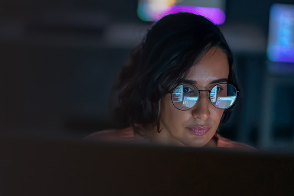 Woman wearing glasses focused on a computer screen