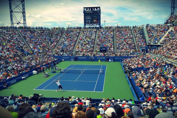Packed stadium watching a tennis match on blue court