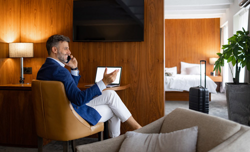 Man in hotel room using laptop and phone