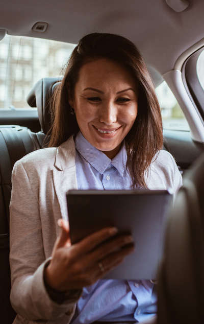 Woman smiling while using tablet in car